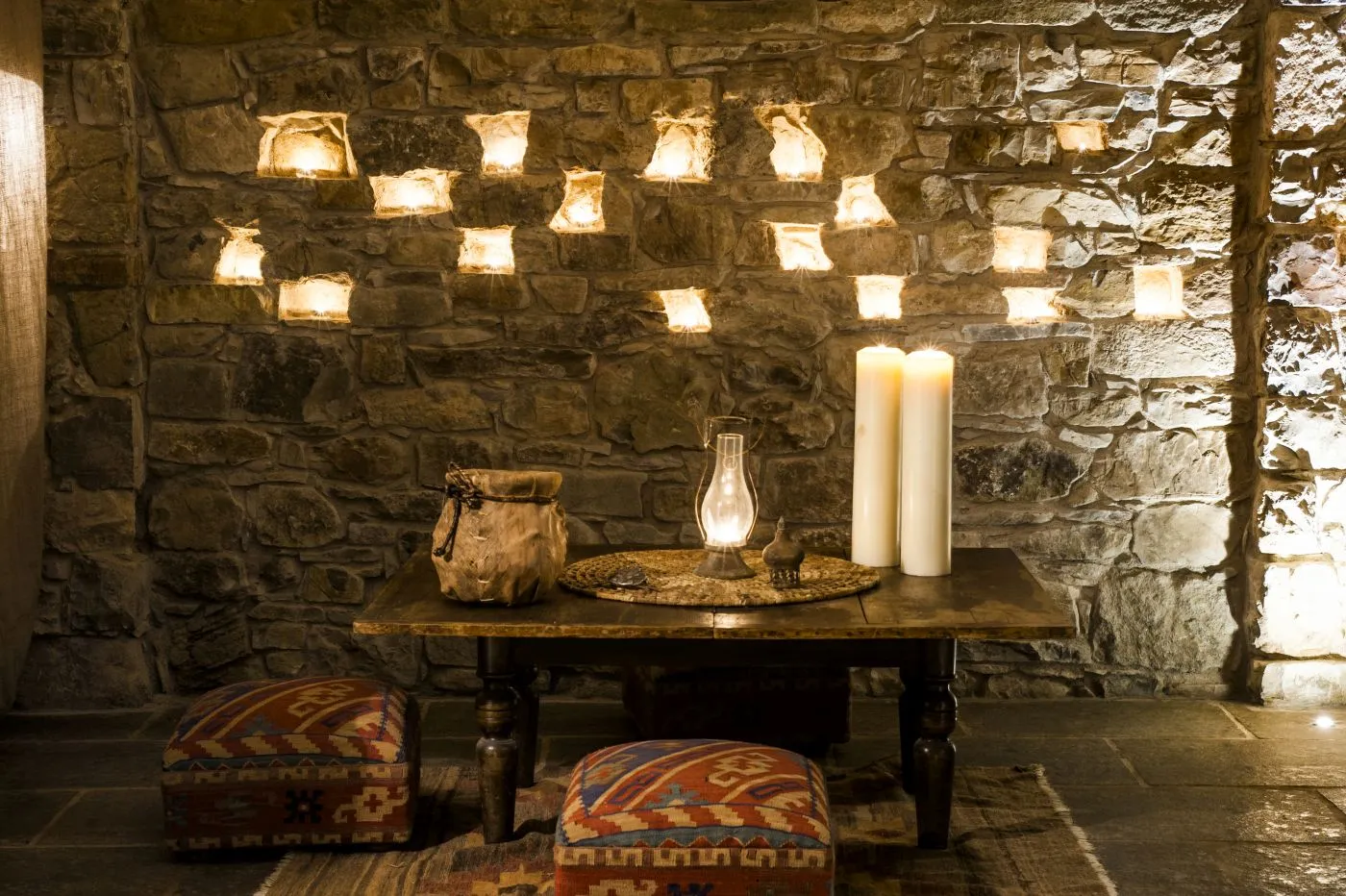Candles glowing in stone wall niches at Eremito