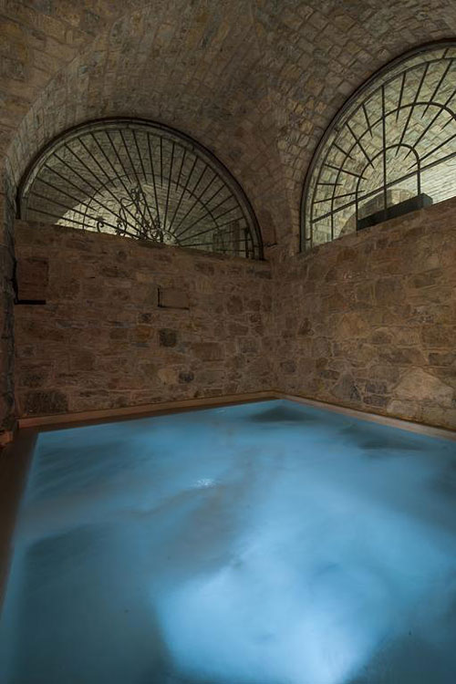 Stone-vaulted heated pool with arched windows