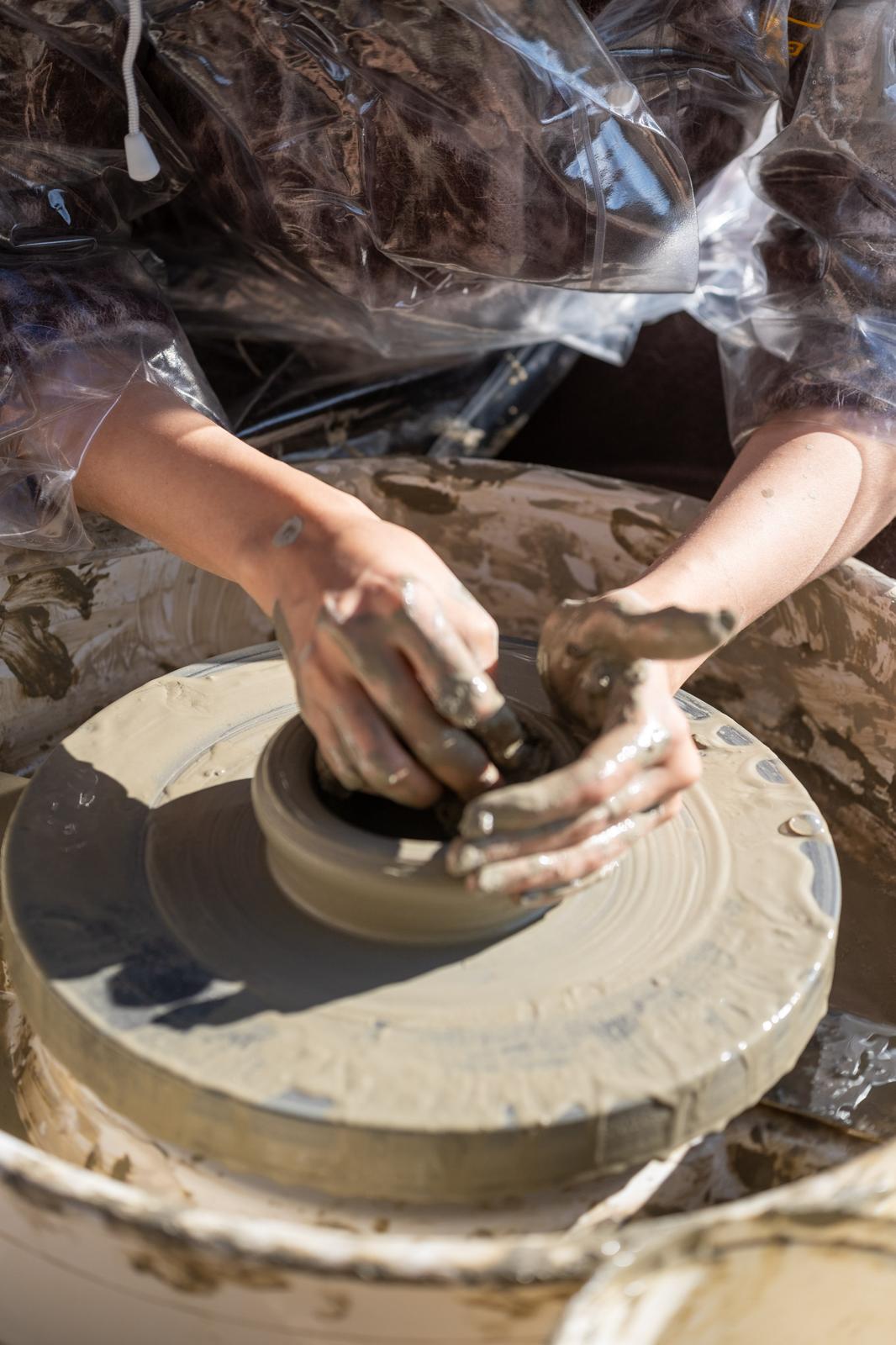 Hands shaping clay on a pottery wheel